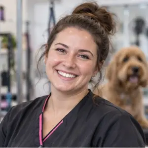 Tierfriseurin im Salon, neben ihr ein kleiner Hund